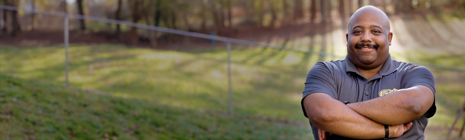 A Critter Control technician smiling in front of a residential yard